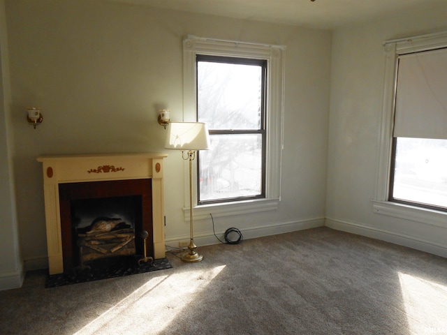 unfurnished living room with carpet, a fireplace with flush hearth, and baseboards