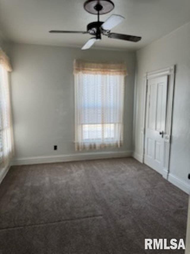 carpeted spare room with a ceiling fan and baseboards