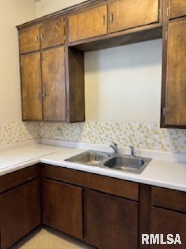 kitchen with light countertops, tasteful backsplash, and a sink