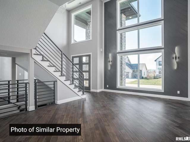 entrance foyer featuring baseboards, a towering ceiling, dark wood-style floors, stairway, and a textured ceiling