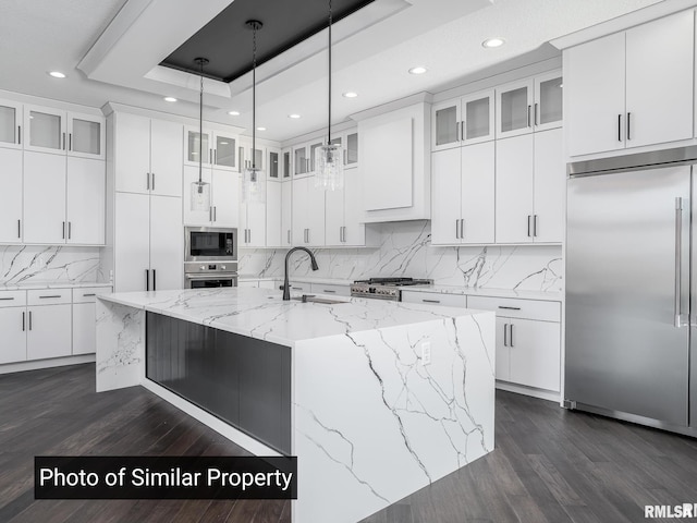 kitchen with white cabinetry, a raised ceiling, and built in appliances