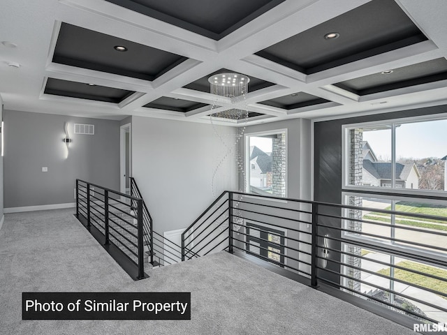 stairway with coffered ceiling, carpet flooring, plenty of natural light, and visible vents