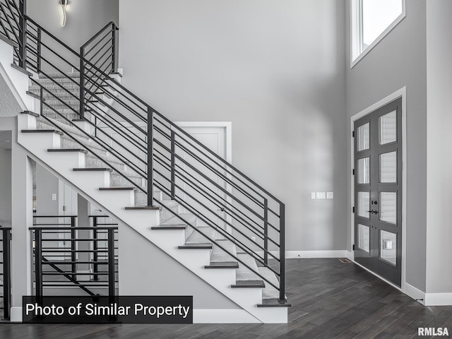 foyer entrance featuring a high ceiling, baseboards, wood finished floors, and french doors