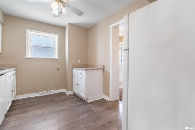 laundry room with ceiling fan, wood finished floors, visible vents, and baseboards