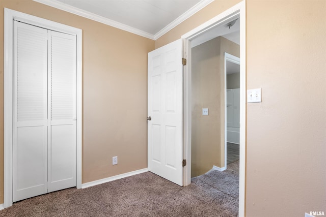 unfurnished bedroom with baseboards, a closet, ornamental molding, and carpet flooring