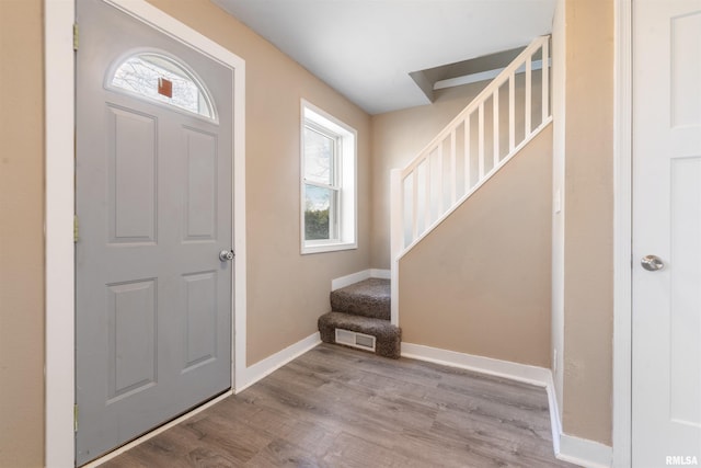 entrance foyer featuring visible vents, stairs, baseboards, and wood finished floors