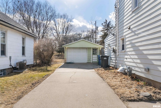 view of side of home featuring concrete driveway, a detached garage, cooling unit, and an outdoor structure