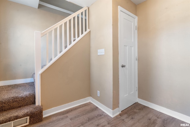 stairs with baseboards, visible vents, and wood finished floors