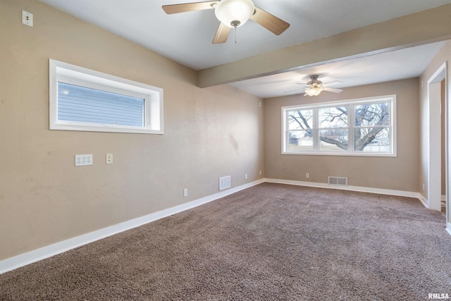 carpeted spare room featuring baseboards, visible vents, and ceiling fan