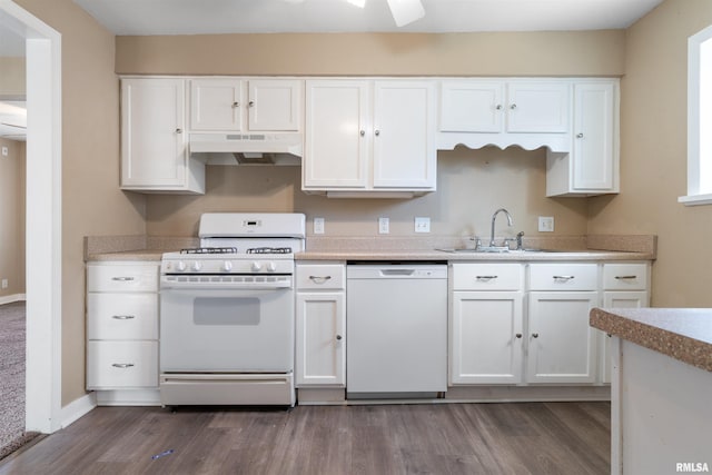 kitchen with white appliances, white cabinets, dark wood-style flooring, under cabinet range hood, and a sink