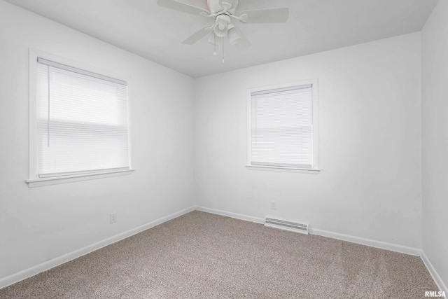 carpeted empty room with a ceiling fan, visible vents, and baseboards