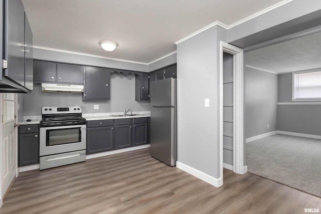 kitchen with under cabinet range hood, a sink, light countertops, appliances with stainless steel finishes, and crown molding