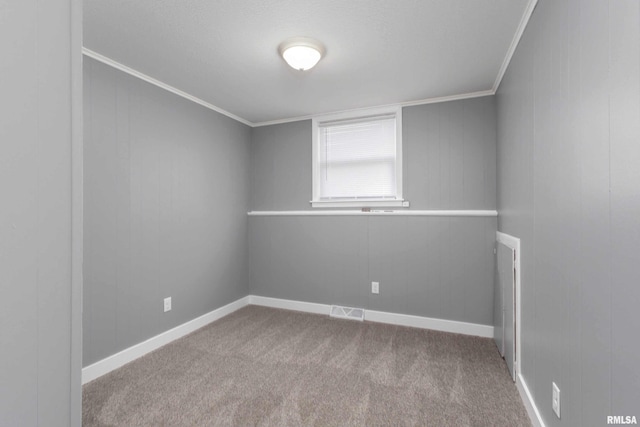 spare room featuring carpet floors, ornamental molding, visible vents, and baseboards