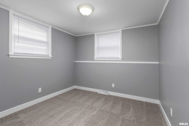 carpeted empty room featuring baseboards, visible vents, and crown molding