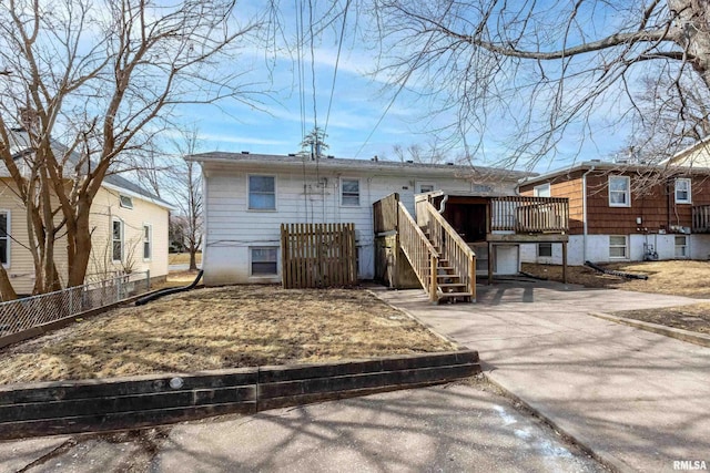 rear view of property with a garage, driveway, fence, and a wooden deck