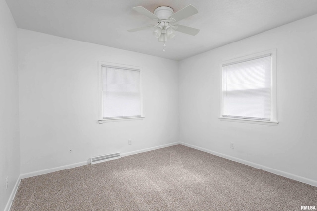 spare room featuring carpet, visible vents, ceiling fan, and baseboards