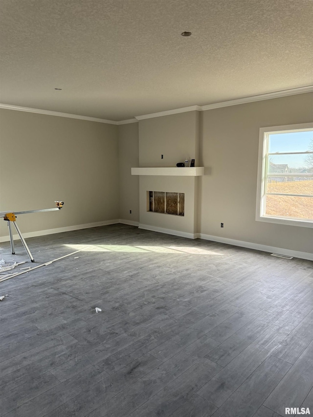 unfurnished living room with baseboards, dark wood finished floors, a fireplace, a textured ceiling, and crown molding