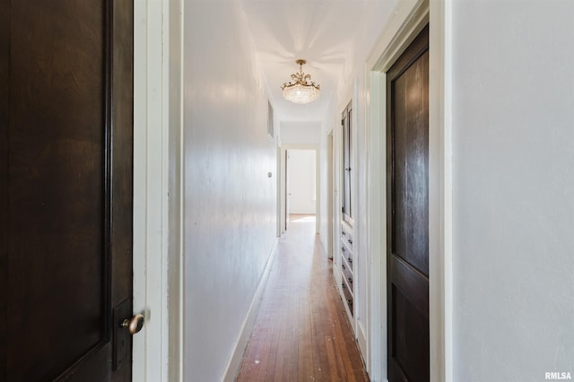 hallway featuring hardwood / wood-style flooring and baseboards