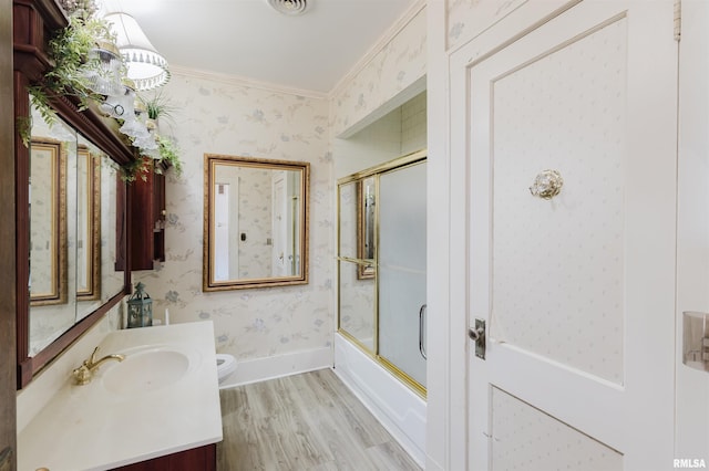 full bath with ornamental molding, vanity, wood finished floors, baseboards, and wallpapered walls