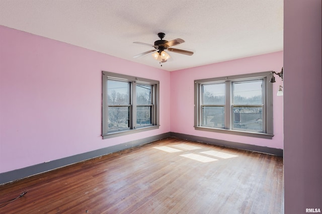 empty room featuring a textured ceiling, ceiling fan, wood finished floors, and baseboards