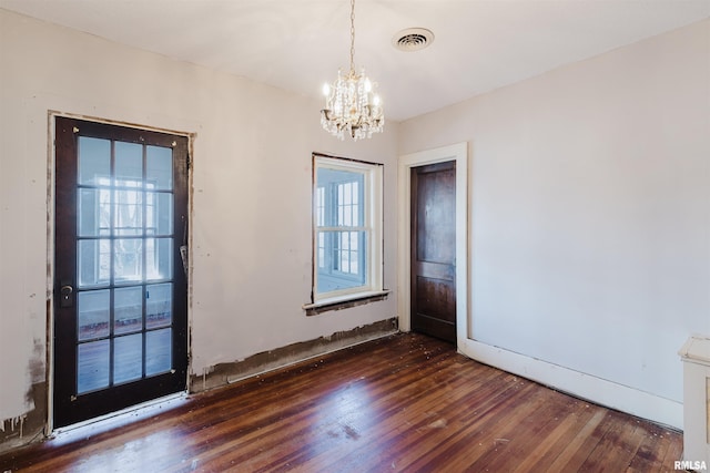 spare room featuring a notable chandelier, visible vents, and hardwood / wood-style floors