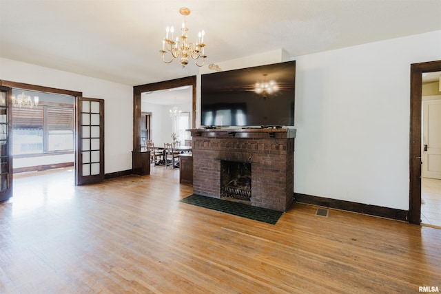 living area with a chandelier, a fireplace, wood finished floors, and visible vents