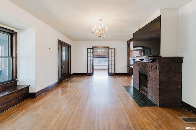 living area featuring a fireplace, plenty of natural light, an inviting chandelier, and wood finished floors