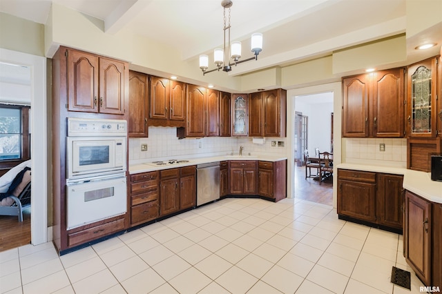 kitchen with a notable chandelier, white appliances, a sink, light countertops, and beamed ceiling