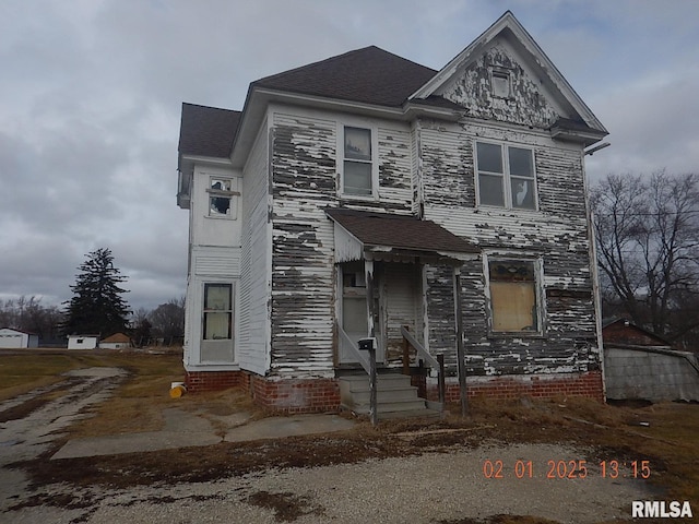 view of front of property featuring entry steps and roof with shingles