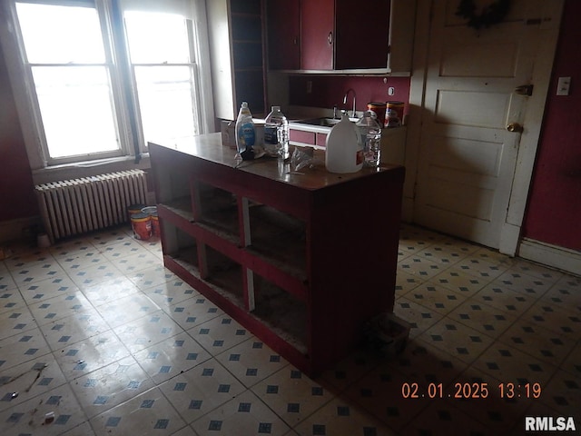 kitchen featuring light floors, light countertops, a sink, and radiator heating unit