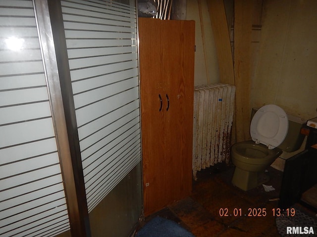 bathroom featuring toilet, radiator heating unit, and wooden walls