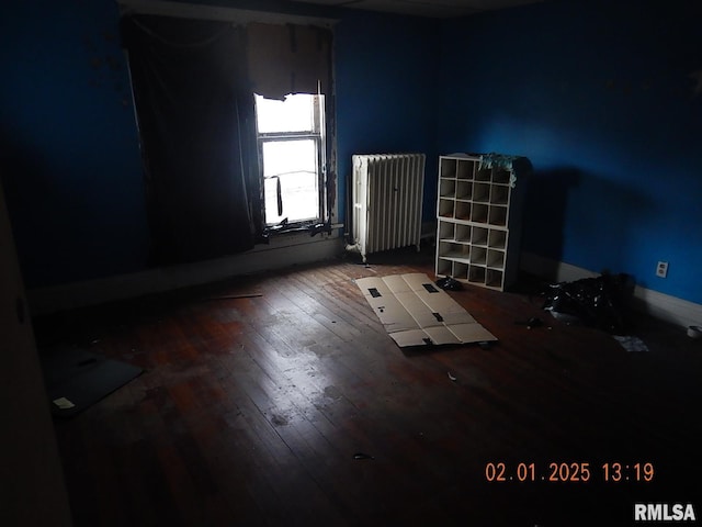 empty room with radiator heating unit and hardwood / wood-style floors