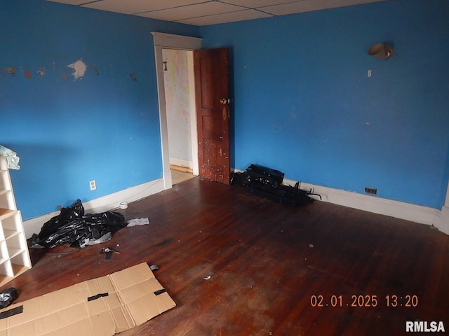 spare room featuring a paneled ceiling, baseboards, and wood finished floors