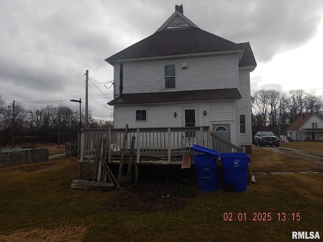 back of house with a yard, roof with shingles, and a wooden deck