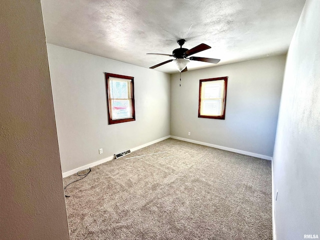 spare room featuring baseboards, visible vents, ceiling fan, and carpet flooring