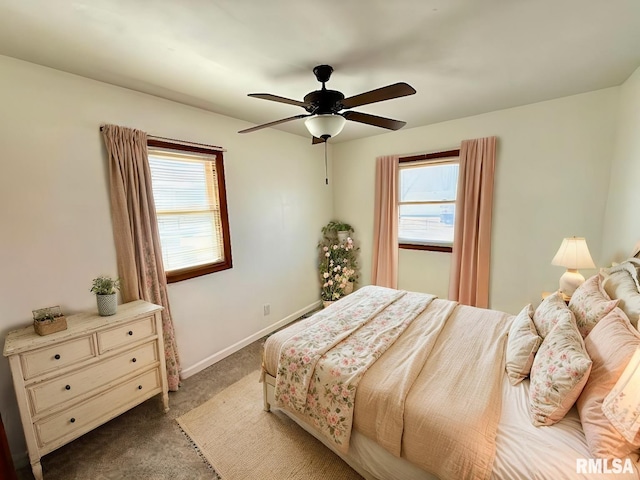 carpeted bedroom with multiple windows, a ceiling fan, and baseboards