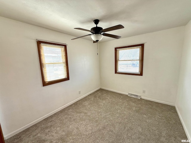 unfurnished room featuring a ceiling fan, dark carpet, visible vents, and baseboards