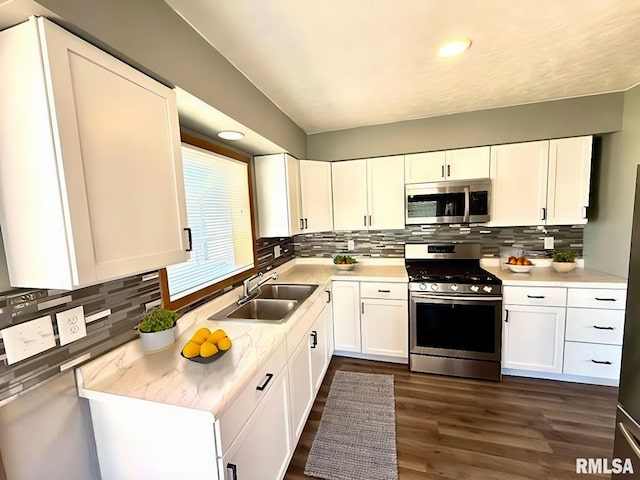 kitchen with white cabinets, dark wood-type flooring, stainless steel appliances, light countertops, and a sink