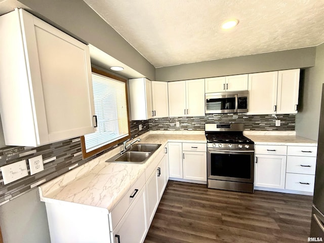 kitchen featuring light countertops, appliances with stainless steel finishes, a sink, and white cabinets