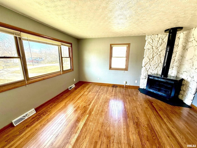 unfurnished living room with wood-type flooring, visible vents, and plenty of natural light