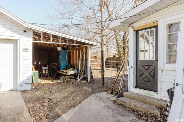 view of exterior entry featuring a garage and fence