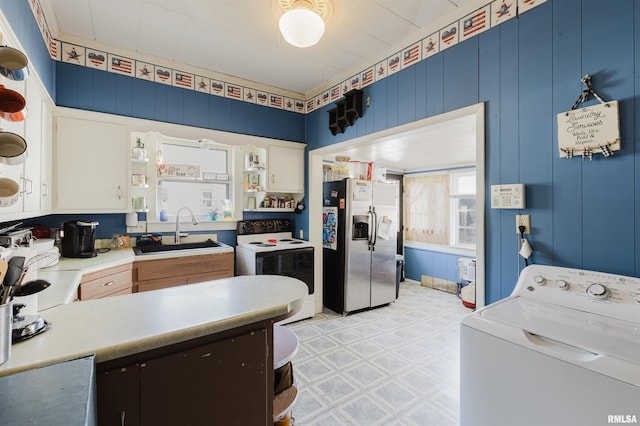 kitchen with light floors, washer / clothes dryer, electric range oven, a sink, and stainless steel fridge with ice dispenser