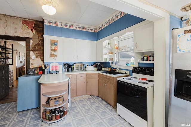 kitchen with electric stove, light floors, light countertops, a sink, and stainless steel fridge