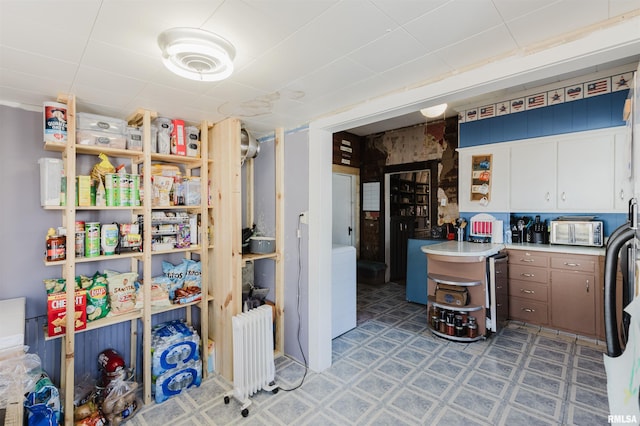 kitchen featuring a toaster, white cabinets, light countertops, radiator, and light floors