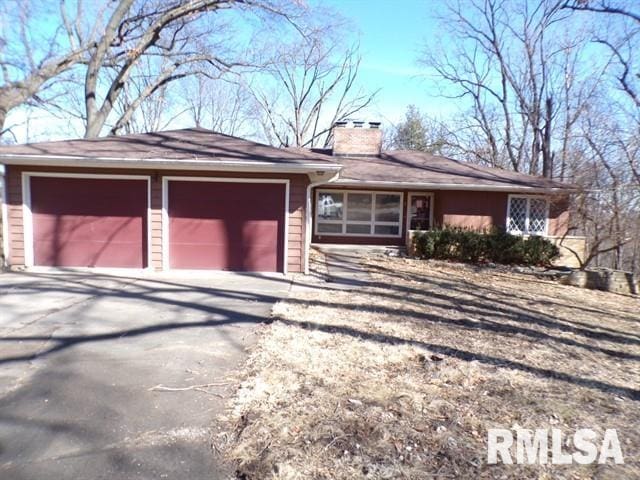 ranch-style home with a garage, concrete driveway, and a chimney