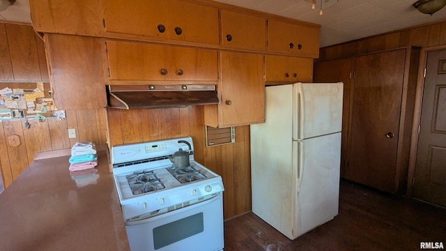 kitchen featuring dark wood-type flooring, white appliances, wood walls, and under cabinet range hood