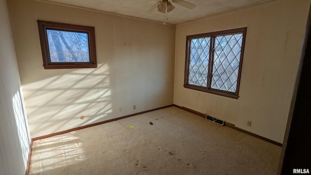 spare room featuring light carpet, ceiling fan, visible vents, and baseboards