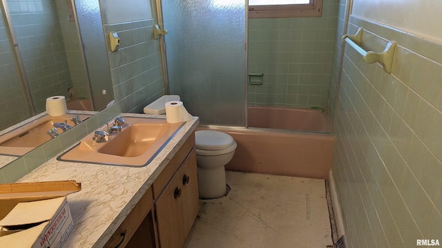 full bath featuring toilet, enclosed tub / shower combo, tile walls, and vanity