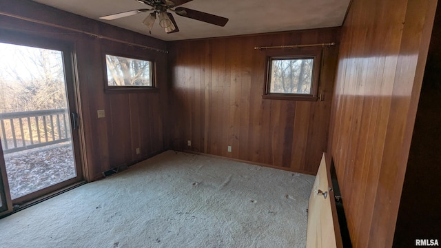 carpeted empty room with ceiling fan, visible vents, and wooden walls