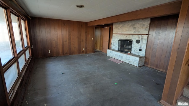 unfurnished living room featuring concrete flooring, a fireplace, and wood walls